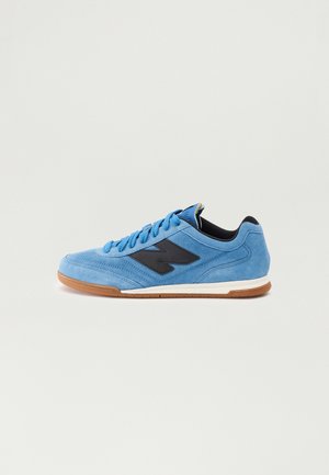 Light blue suede sneakers with black logo, round toe, and rubber sole; features blue laces and padded collar for comfort.