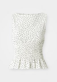 Witte mouwloze top met een gestructureerd oppervlak, voorzien van zwarte stippen en een ruchesrand. Het ontwerp heeft een gerimpelde lijf. 