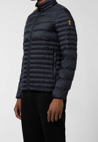 Granatowa puchowa kurtka z wysokim kołnierzem, poziomym pikowaniem i naszywką z logo na rękawie. Miękka, gładka tekstura o dopasowanym kroju.