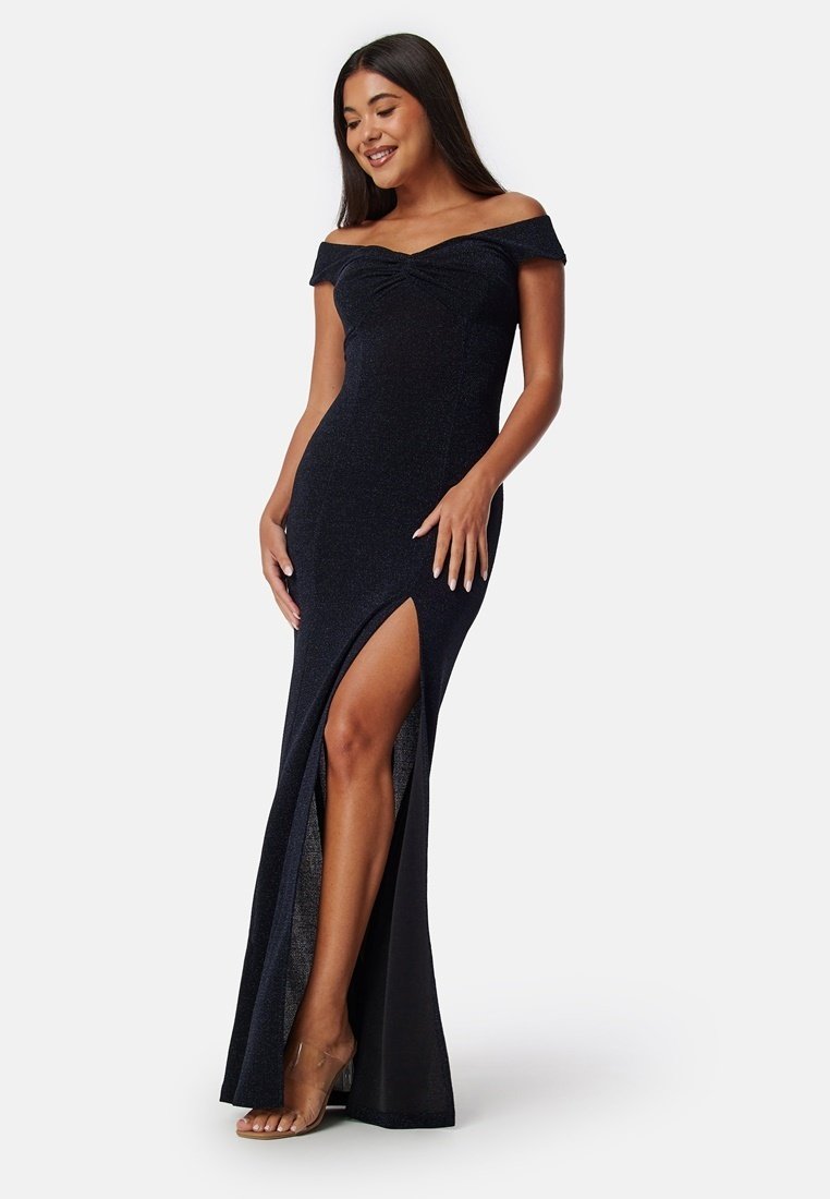Svart off-shoulder kvällsklänning med ett figurnära liv, hög slits och glittrande textur. Golvlängdens design ökar elegansen och silhuetten.