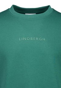 Grön crewneck t-shirt tillverkad av bomullsblandning, med en texturerad "LINDHBERGH"-logotyp över bröstet, slätt tyg och korta ärmar.