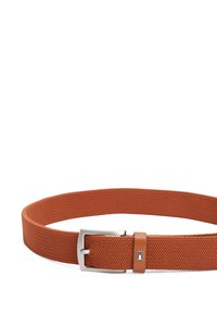 Ceinture tissée orange avec une boucle en métal argenté et une accent en cuir. Elle présente un tissu texturé et un petit logo dans des couleurs contrastées.