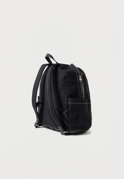 Musta reppu, jossa on etutasku, ylävetoketju, pehmustetut olkahihnat ja näkyvät beigen väriset saumat yksivärisellä vaalealla taustalla.