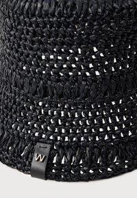 Sombrero tipo pescador de paja negra tejida con patrón de tejido abierto y pequeña etiqueta de cuero negra con una "W" plateada en el ala.