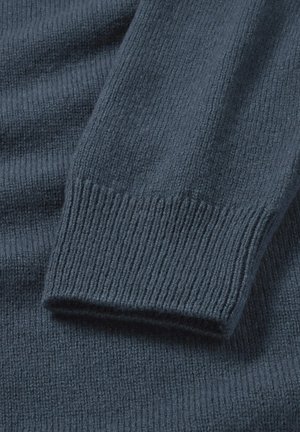 Donkerblauwe gebreide trui met geribbelde manchetten en textuur. Zacht materiaal, met een strak ontwerp en subtiele variatie in de gebreide patronen.