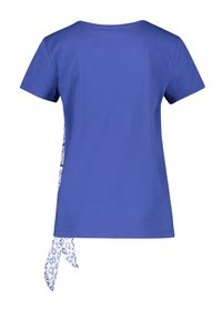 Blue short-sleeve T-shirt with a round neckline, featuring a white and blue patterned fabric tie hanging from the side seam.