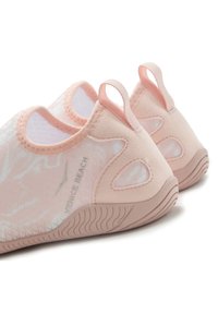 Light pink slip-on shoes with a textured surface, elasticized openings, and looped heel pulls. Features a smooth sole and breathable fabric.