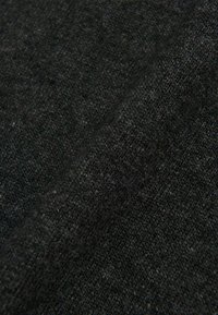 Schwarzer Strickstoff mit einer strukturierten Oberfläche, die feine Fasern zeigt, aus einem Winkel aufgenommen, der sein weiches Aussehen und seine Dichte betont.