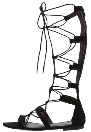 Sort gladiatorsandal i knælængde med flad sål og flere tynde snørestraps.