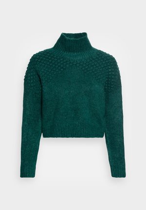Ciemnozielony dziergany sweter z teksturowanym wzorem bobble na ramionach i klatce piersiowej, wysokim prążkowanym kołnierzem, długimi rękawami i krótkim dołem.