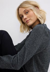 Pullover in maglia a maniche lunghe, nero e argento macchiato, con texture a coste e leggere arricciature sulle cuciture delle spalle.
