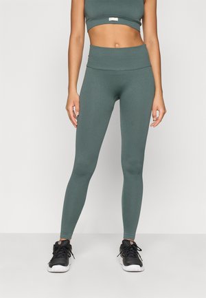 Ribbet grøn athleisure sæt med en cropped top og højtaljede leggings. Materialet ser ud til at være strækbart. Bæres med sorte træningssko.