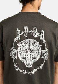 Zwarte katoenen T-shirt met een grote witte tijgerafbeelding omringd door rozen en yin-yang symbolen. Heeft een ronde halslijn en korte mouwen.