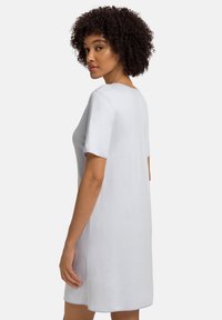 Svetle šedé šaty s krátkým rukávem, které mají volný střih, měkkou strukturu a kulatý výstřih s mírným zakřivením na spodním lemu.