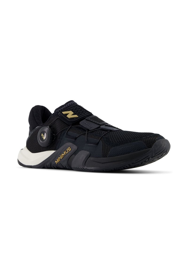 Zapatilla deportiva negra con parte superior de malla, suela acolchada y correa de Velcro. Presenta el logo "Minimus" en dorado en el lateral y suela de goma texturizada.