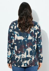 Camicia button-up morbida con un motivo astratto multicolore in navy, crema e bordeaux. Maniche lunghe con dettagli ai polsini.