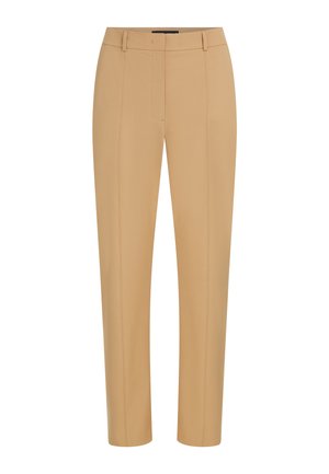 Pantalon beige ajusté sur mesure avec coutures frontales, passants de ceinture et fermeture frontale dissimulée.