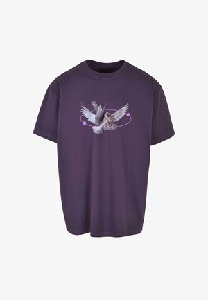 Violetti puuvillapaita, jossa on graafinen kuvasto siivillään olevan linnun kanssa, ja ympyrämuotoisen designin kaksi korostusta taustalla. Lyhyet hihat, rento fit.