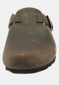 Zoccolo in pelle marrone con punta rotonda, due cinturini regolabili e una suola nera testurizzata. Presenta una superficie liscia con finitura opaca.