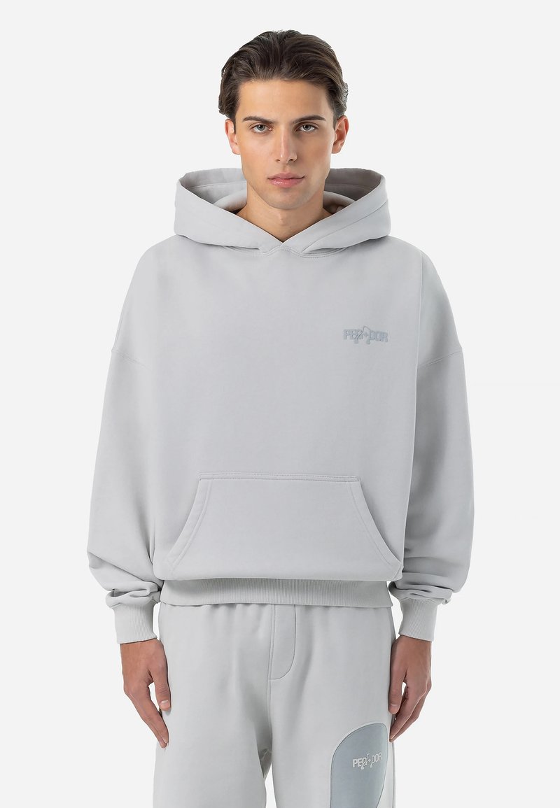 Lichtgrijze hoodie van zacht materiaal met een voorkeurszak en een capuchon met trekkoord, met subtiele branding op de borst.