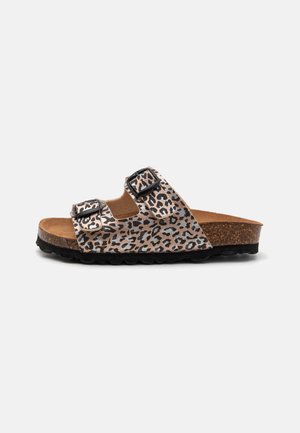 Schlittschuhsandale mit Leopardenmuster, zwei verstellbaren schwarzen Schnallen, einem Korkfußbett und einer strukturierten schwarzen Außensohle. Farbpalette umfasst Beige und Schwarz.