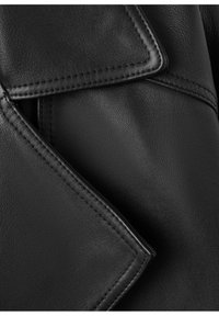 Prenda de cuero negro que muestra un primer plano detallado de solapas superpuestas con costuras visibles y superficie texturizada.