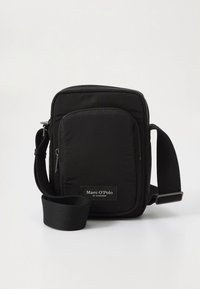 Schwarze kompakte Umhängetasche mit Reißverschluss-Vordertasche und verstellbarem Riemen, vorne mit Marc O’Polo-Label gebrandet.