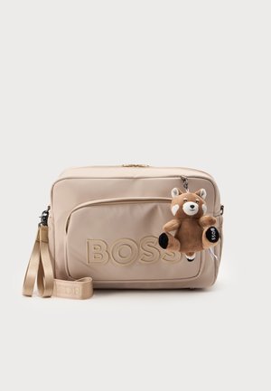 Borsa beige BOSS con tasca frontale con cerniera, logo ricamato e un piccolo portachiavi in peluche a forma di volpe attaccato di lato.