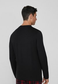 Černé tričko s dlouhým rukávem a kulatým výstřihem, vyrobené z bavlněné směsi. Hladká textura, minimalistický design a volný střih.