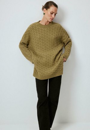 Olijfgroen gebreid cable-knit sweater met een relaxte fit en ribbelrand, gecombineerd met zwarte wijd uitlopende broek. Opvallende textuur en oversized mouwen.
