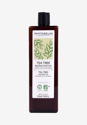 Bottiglia di plastica marrone scuro con un tappo a scatto nero. L'etichetta frontale presenta grafica botanica verde e testo che indica gel doccia al tea tree, 500ml.