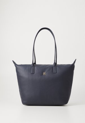 Sac cabas en cuir bleu marine avec doubles longues anses, fermeture éclair dorée et petit emblème logo doré au centre devant.