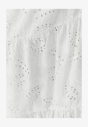 Valge tikandiga kangas lille- ja lehemustritega, millel on lõigatud detailid ja alumises osas kortsuline tekstuur.