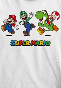 Grafický tričko Super Mario, na kterém je Mario v červené, Luigi v zelené, Yoshi v zelené a Toad, s nápisem "SUPER MARIO" v barevných blokových písmenech.