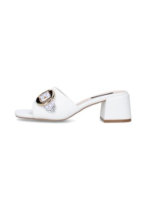 Mule bianca open-toe con tacco a blocco, fibbia circolare dorata e dettaglio decorativo con sciarpa sulla fascia superiore.