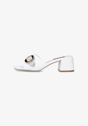 Mule bianca open-toe con tacco a blocco, fibbia circolare dorata e dettaglio decorativo con sciarpa sulla fascia superiore.