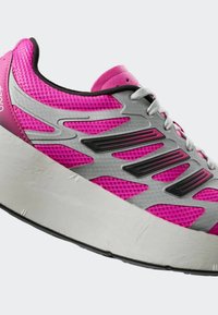 Bežecká obuv s ružovým sieťovaným zvrškom, sivými syntetickými doplnkami, čiernymi akcentmi a hrubou bielou podrážkou. Obsahuje šnúrky a polstrovaný golier.