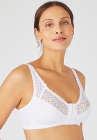 Sujetador de algodón suave con detalles de encaje blanco. Presenta un diseño de escote en V, bordes ondulados y paneles de encaje floral en la parte frontal.