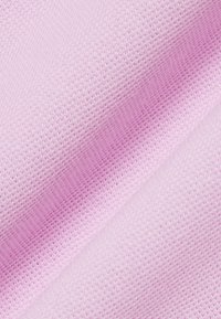 Gros plan sur un tissu tricoté doux de couleur rose clair montrant une texture tissée détaillée et des plis délicats.