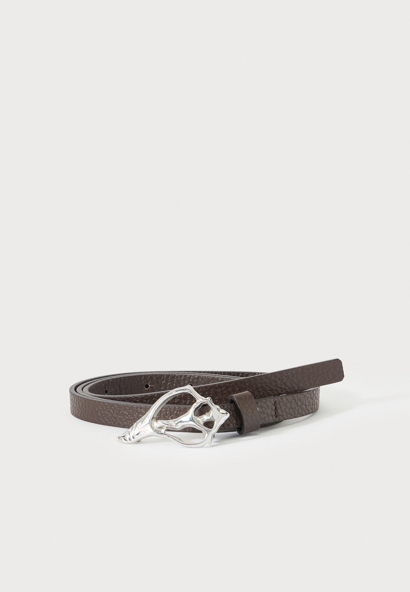 Ceinture en cuir brun foncé texturé avec une boucle argentée unique de forme abstraite, enroulée sur un fond clair uni.