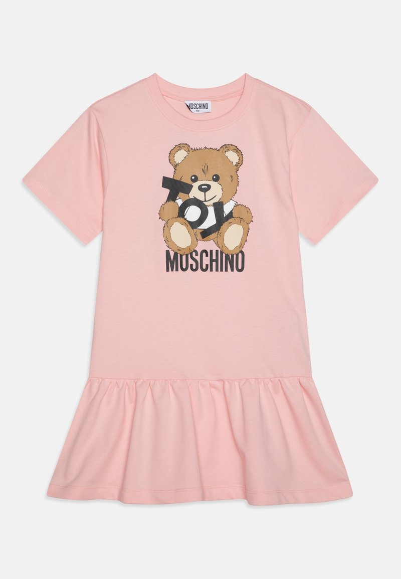 Robe rose à manches courtes avec ourlet volanté, représentant un ours en peluche tenant un texte noir et "Moschino" écrit en dessous.