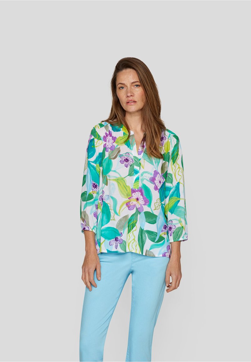 Bunt gemusterte Bluse mit einem Blumenmuster in Grüntönen, Blau, Lila und Weiß. Lange Ärmel mit elastischen Bündchen.