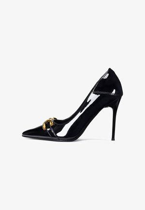 Čierna lodička z lesklej koženky s vysokým podpätkom, špicatou špičkou a zlatým pásikom. Elegantný dizajn s úzkym ihličkovým podpätkom.