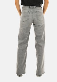 Jean gris taille haute avec une coupe droite, doté de cinq poches et d'un fini texturé subtil. Aucun logo ou motif visible.