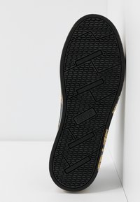 Černá pryžová podrážka boty s texturovaným vzorem a logem, s oblým tvarem a zesílenými okraji pro odolnost.