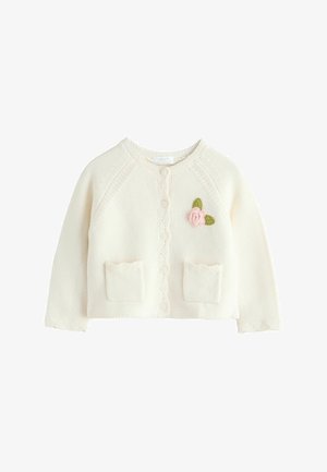 Krēmkrāsas adīts kardigans ar apaļu izgriezumu, viļņotu maliņu, divām priekšpuses kabatām un rozā izšūtu rozes detaļu kreisajā pusē.