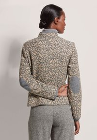 Wolmix jas met een geometrisch bladvormig patroon in beige en grijs, voorzien van grijze elleboogpatches en een ontwerp met hoge kraag.
