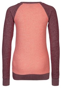 Top de manga raglán en color coral con acentos en granate. La tela texturizada presenta colores contrastantes en las mangas y el dobladillo. Cuello redondo clásico.