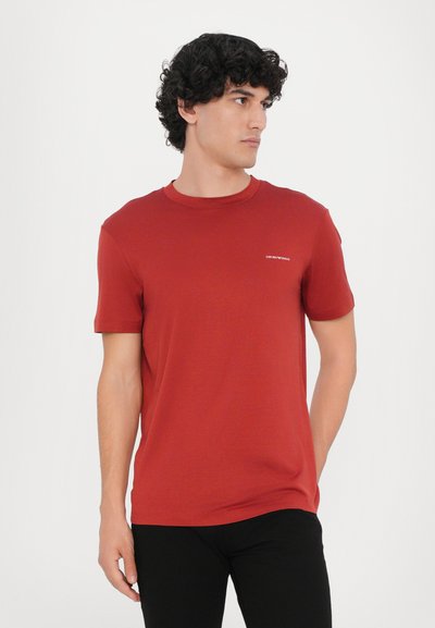 Rotes T-Shirt aus Baumwolle mit Rundhalsausschnitt und kurzen Ärmeln. Kleines, weißes Logodetail auf der linken Brust. Glatte Textur.