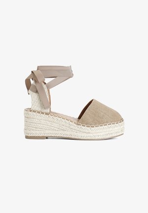 Beige linnen espadrille-wedge met een geweven jute zool, bovenkant van stof en bijpassende enkelbandjes. Heeft een ronde neus en een gestructureerde hak.